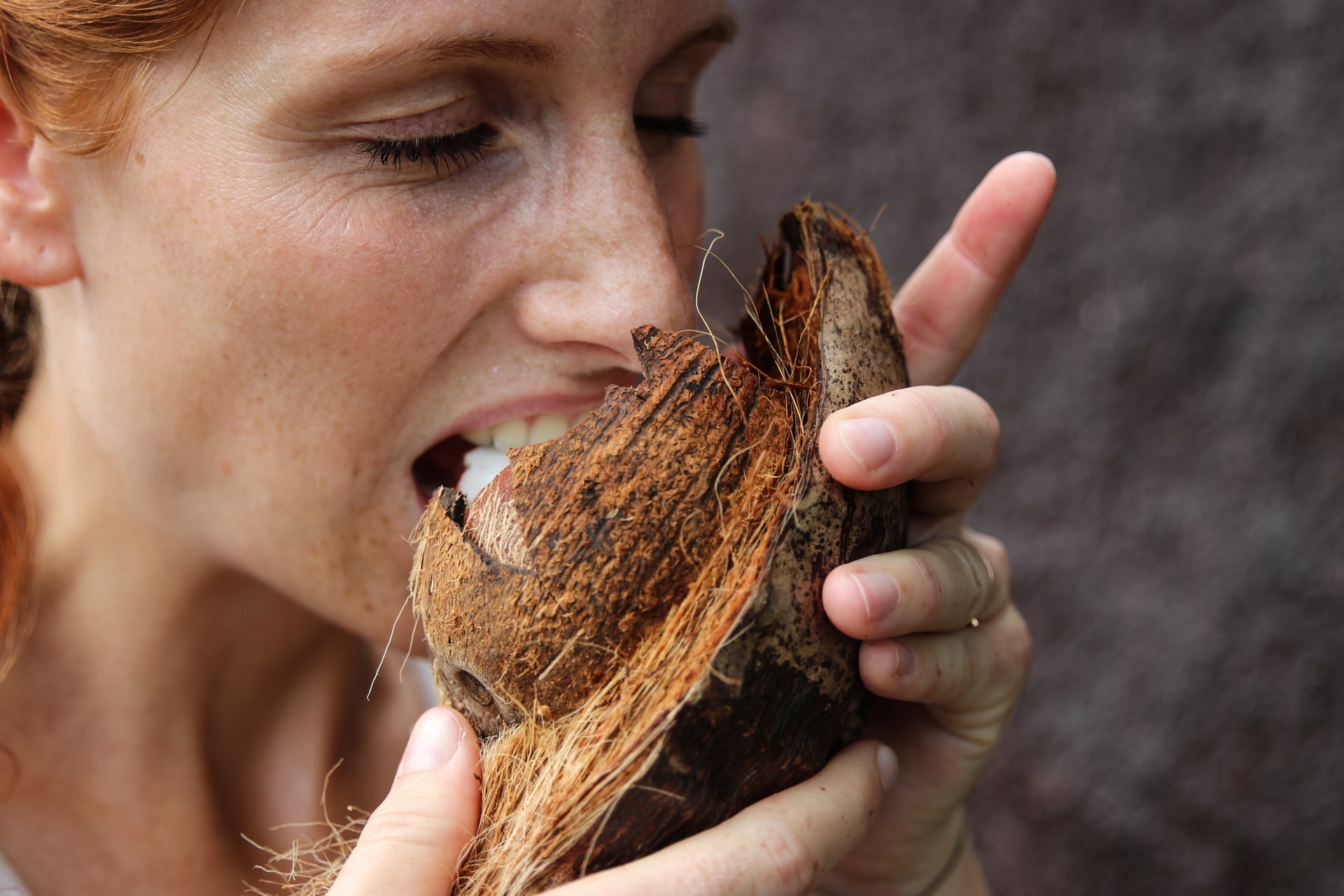 woman taking a bite of coconut meat
